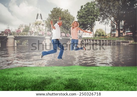 Excited couple cheering and jumping against sunny day by the river