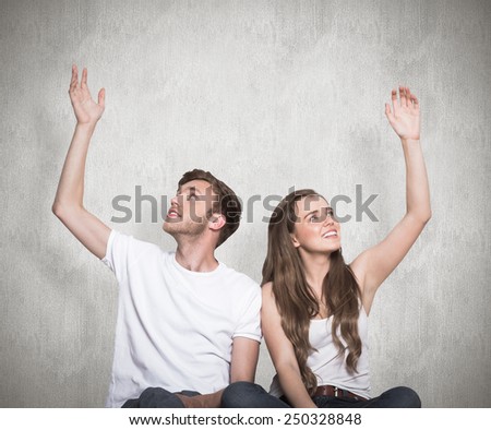 Happy young couple with hands raised against weathered surface