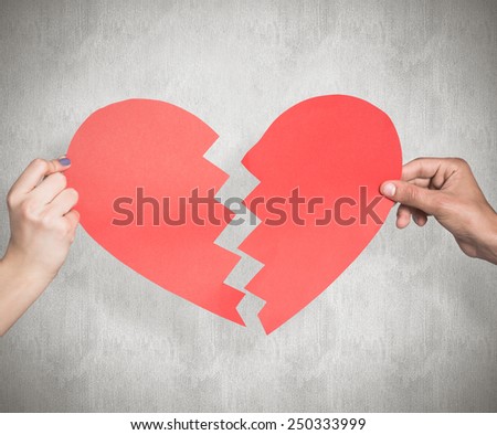 Two hands holding broken heart against weathered surface