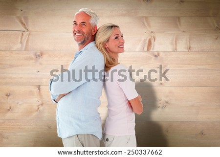 Smiling couple standing leaning backs together against bleached wooden planks background