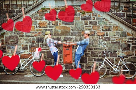 Hip young couple dancing by brick wall with their bikes against hearts hanging on a line