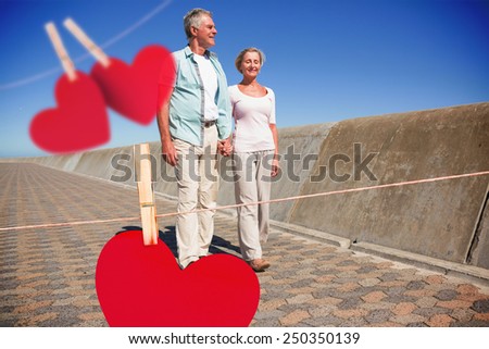 Happy senior couple walking on the pier against hearts hanging on a line