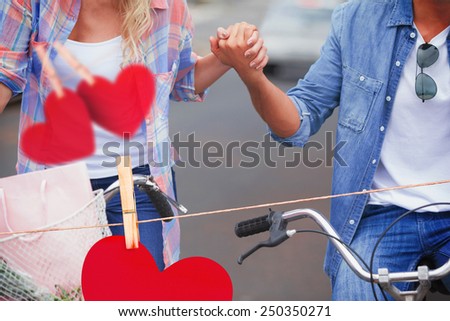 Hip young couple going for a bike ride against hearts hanging on a line