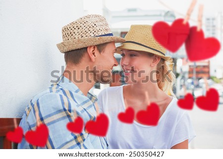 Young hip couple sitting on bench about to kiss against hearts hanging on a line
