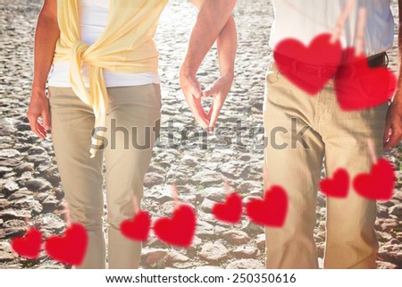 Happy senior couple touching hands against hearts hanging on a line