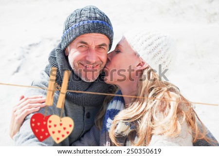 Attractive couple on the beach in warm clothing against hearts hanging on the line