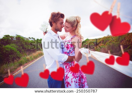 Cute couple standing on the road hugging against hearts hanging on a line