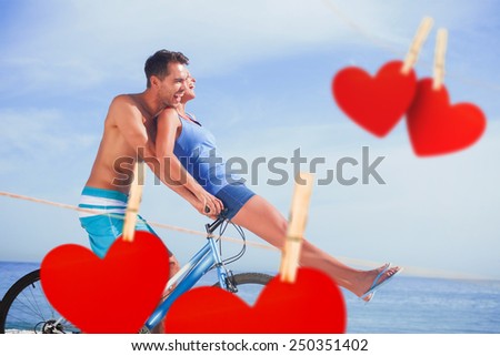 Man giving girlfriend a lift on his crossbar against hearts hanging on a line