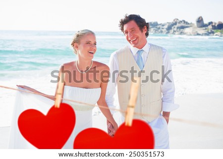 Newlyweds walking hand in hand and laughing against hearts hanging on a line