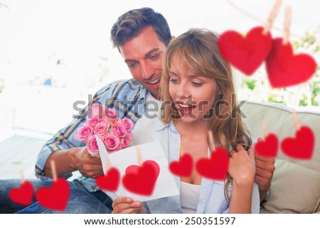 Loving couple with flowers and greeting card against hearts hanging on a line