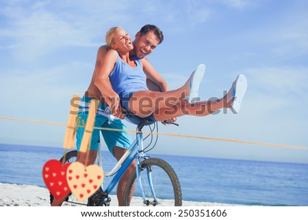 Happy man giving girlfriend a lift on his crossbar against hearts hanging on the line