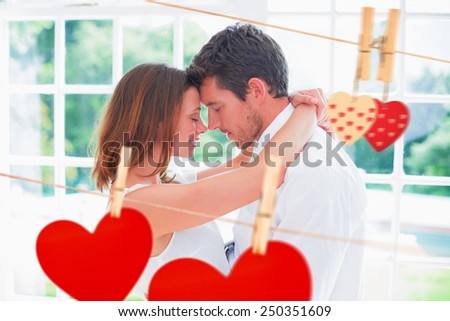 Loving young couple with arms around against hearts hanging on the line
