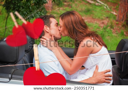 Beautiful couple kissing in back seat against hearts hanging on a line