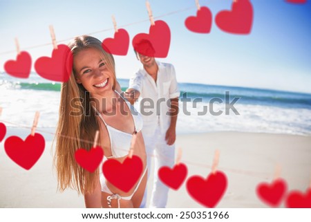 Woman smiling at camera with boyfriend holding her hand against hearts hanging on a line