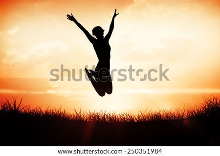 Gorgeous fit blonde jumping with arms out against orange sunrise