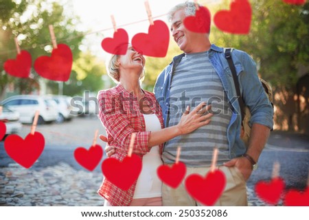 Happy mature couple hugging in the city against hearts hanging on a line