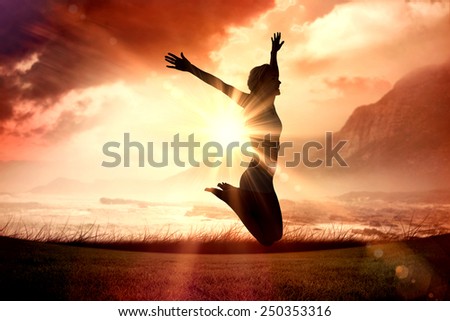 Gorgeous fit blonde jumping with arms out against sunrise over magical sea
