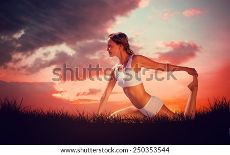 Gorgeous fit blonde in seated yoga pose against red sky over grass