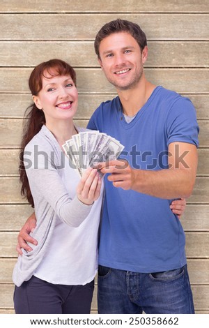 Couple holding fan of cash against wooden planks