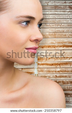 Smiling blonde natural beauty against wooden background in pale wood