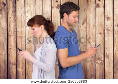 Couple both sending text messages against wooden planks