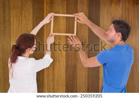 Couple deciding to hang picture against wooden surface with planks