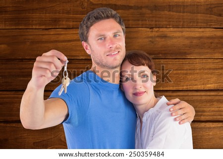 Couple holding keys to home against overhead of wooden planks