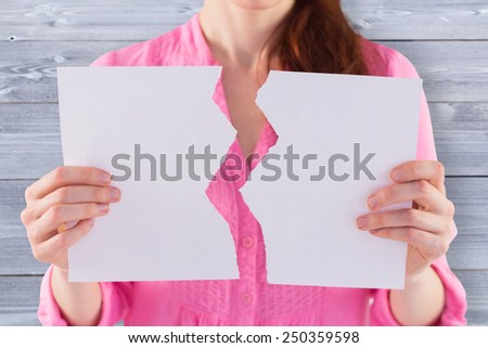 Woman holding torn sheet of paper against bleached wooden planks background