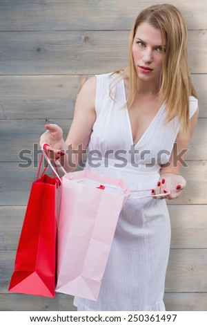 Blonde with shopping bags against pale grey wooden planks