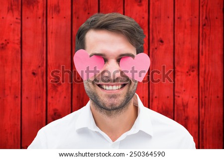 Handsome man with hearts over his eyes against wooden background in red