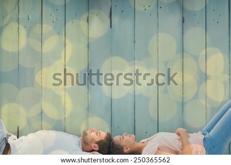 Attractive young couple lying down against blurry yellow christmas light circles