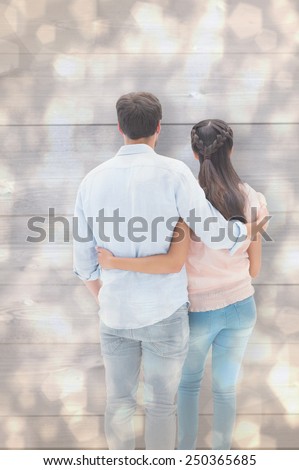 Attractive young couple standing with arms around against light glowing dots design pattern