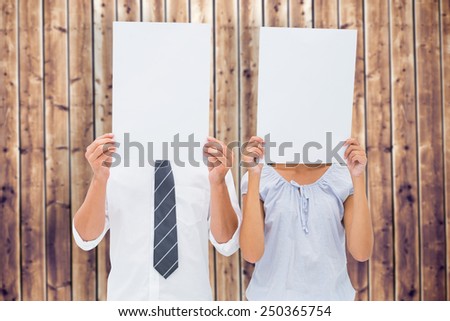 Couple holding paper over their faces against wooden planks background