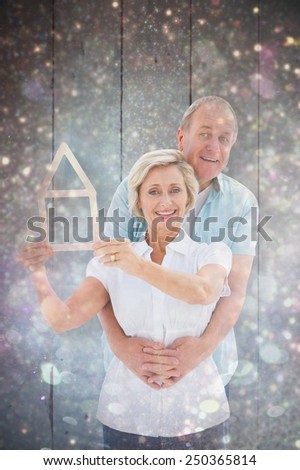 Happy older couple holding house shape against white snow and stars on black