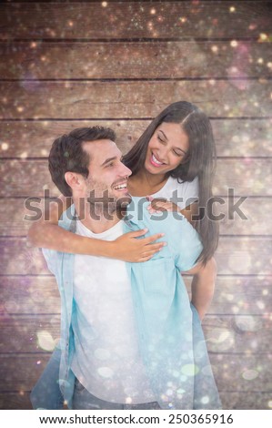 Happy casual man giving pretty girlfriend piggy back against white snow and stars on black