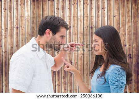 Angry couple pointing at each other against wooden planks