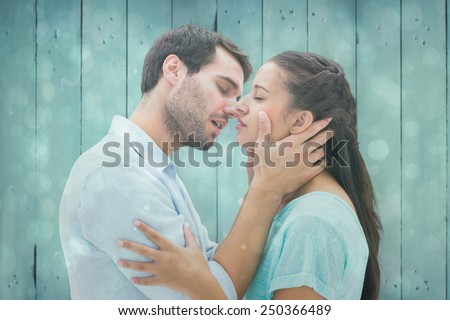 Attractive young couple about to kiss against blue abstract light spot design