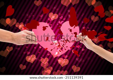 Hands holding two halves of broken heart against digitally generated girly heart design