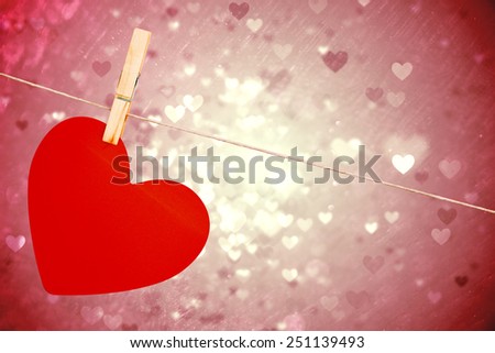 Heart hanging on line against valentines heart design