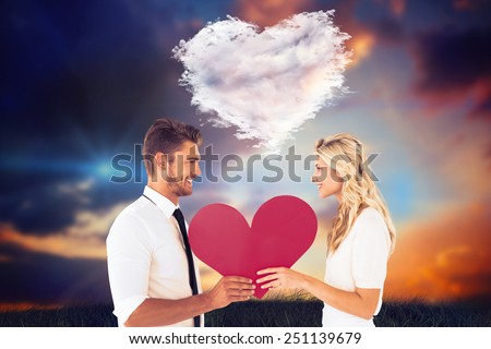 Attractive young couple holding red heart against cloud heart