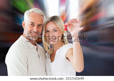 Happy couple showing their new house key against blurry new york street