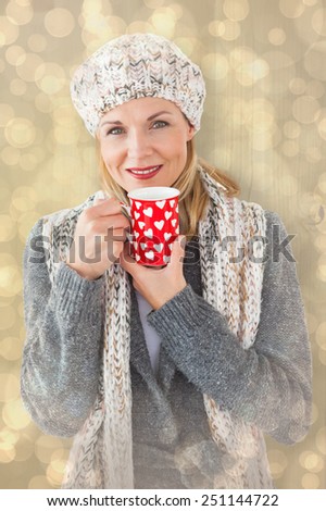 Smiling woman in winter fashion looking at camera with mug against light glowing dots design pattern