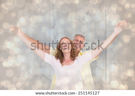 Casual couple smiling with arms raised against light glowing dots design pattern