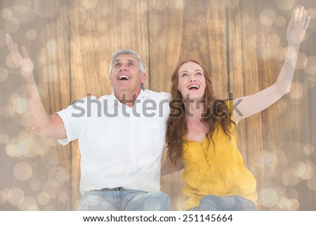 Casual couple smiling with arms raised against light glowing dots design pattern