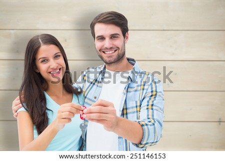Happy young couple showing new house key against bleached wooden planks background