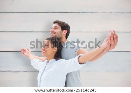 Cute couple standing with arms out against painted blue wooden planks