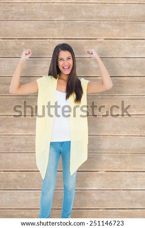 Happy casual woman cheering at camera against wooden planks