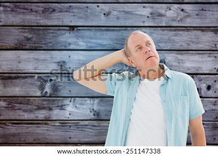 Thoughtful older man looking up against grey wooden planks
