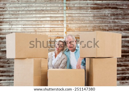 Stressed older couple with moving boxes against wooden planks