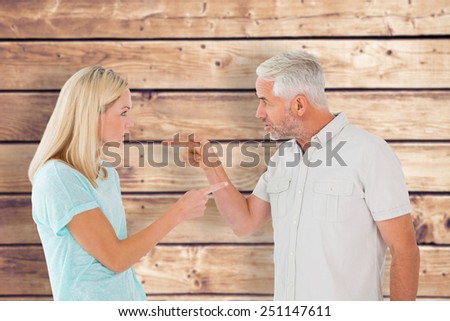 Unhappy couple having an argument against wooden planks background